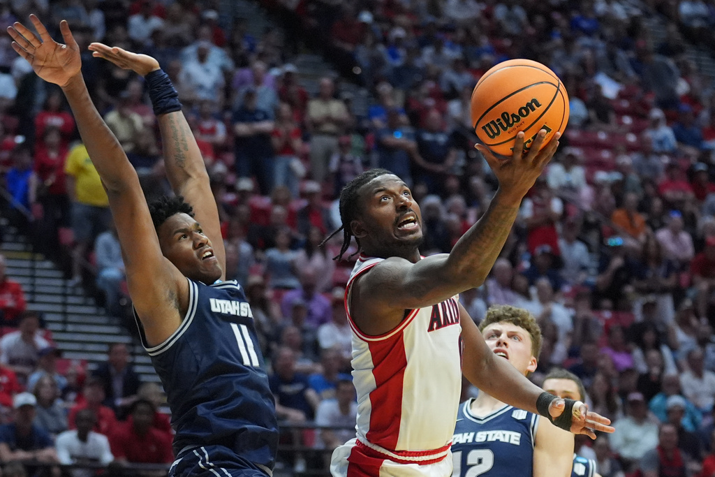 Arizona guard Jaden Bradley (0) shoots around Utah State forward Garry Clark (11) during the second half of a game in the second round of the NCAA college basketball tournament Sunday, March 22, 2026, in San Diego. (AP Photo/Marcio Jose Sanchez)