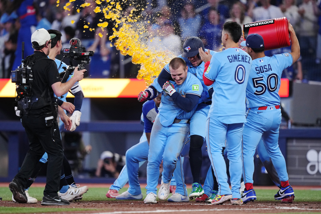 Toronto Blue Jays' Daulton Varsho (left) celebrates his walk-off grand slam against the Tampa Bay Rays with teammates during 10th inning MLB baseball action in Toronto on Wednesday, May 13, 2026. (Nathan Denette/The Canadian Press via AP)