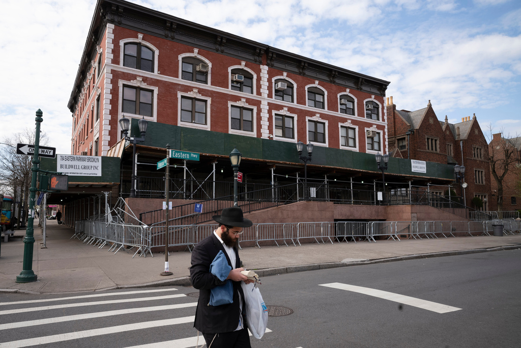FILE - A man passes the Chabad-Lubavitch World Headquarters in the Crown Heights neighborhood of Brooklyn, April 7, 2020 in New York. (AP Photo/Mark Lennihan, File)