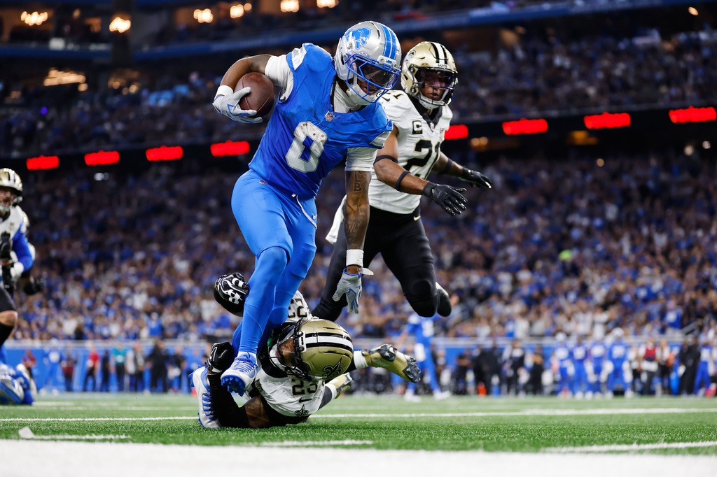 Detroit Lions running back Jahmyr Gibbs (0) carries against New Orleans Saints safety Julian Blackmon (23) and Justin Reid in the first half of an NFL football game, Sunday, Sept. 13, 2026, in Detroit. (AP Photo/Rey Del Rio)