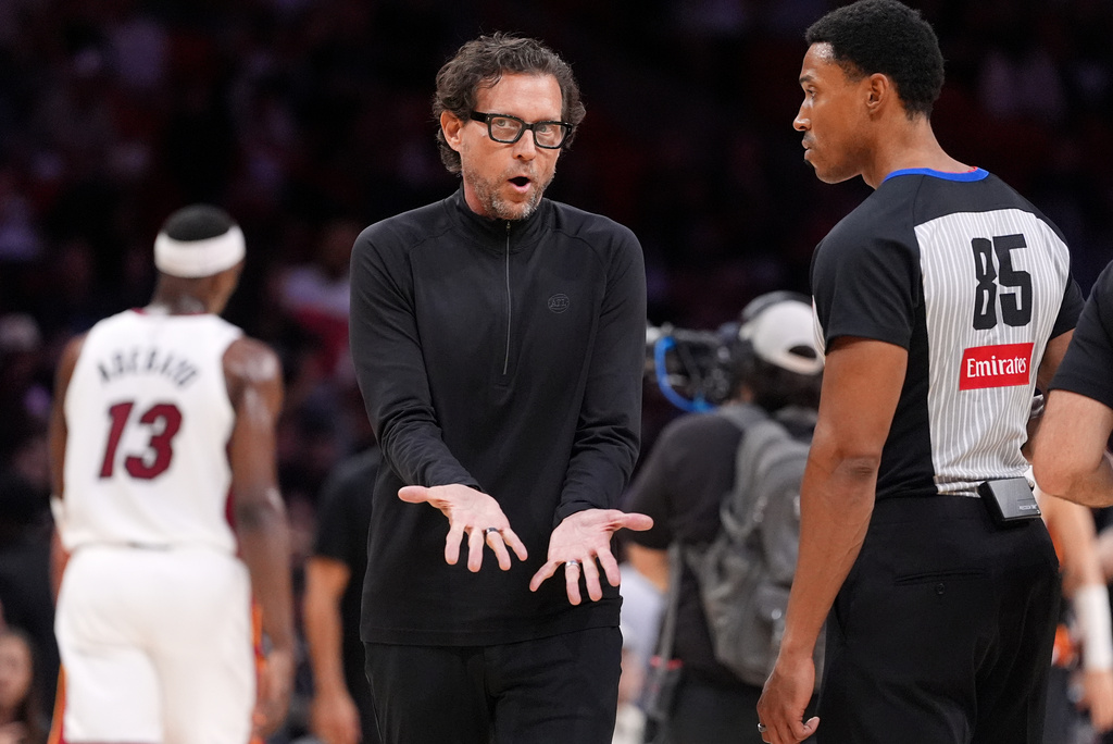 Atlanta Hawks head coach Quin Snyder, center, talks with referee Robert Hussey (85) during the first half of an NBA basketball game against the Miami Heat, Sunday, April 12, 2026, in Miami. (AP Photo/Rebecca Blackwell)
