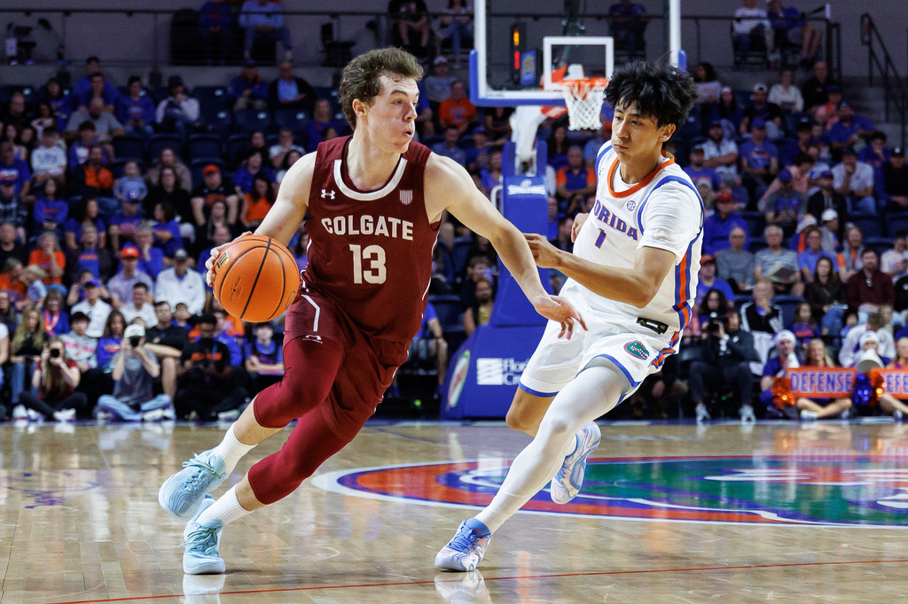 Colgate guard Kyle Carlesimo (13) dribbles past Florida guard Xaivian Lee (1) during the first half of an NCAA college basketball game Sunday, Dec. 21, 2025, in Gainesville, Fla. (AP Photo/Chris Watkins)