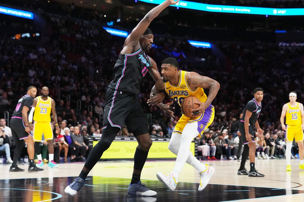 Los Angeles Lakers guard Marcus Smart, right, drives to the basket as Miami Heat center Bam Adebayo, left, defends during the first half of an NBA basketball game, Thursday, March 19, 2026, in Miami. (AP Photo/Lynne Sladky)