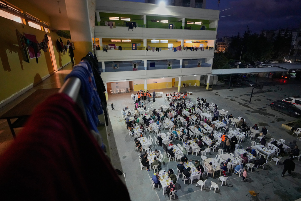 Displaced people who fled Israeli strikes from south Lebanon, gather for Iftar, the Ramadan fast-breaking meal, at a school playground turned into a shelter, in the southern port city of Sidon, Lebanon, Monday, March 16, 2026. (AP Photo/Mohammed Zaatari)