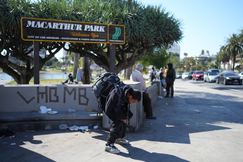 A man holding a pipe stands hunched over at MacArthur Park after federal authorities made arrests on charges related to selling illicit drugs on Wednesday, May 6, 2026, in Los Angeles. (AP Photo/Jae C. Hong)