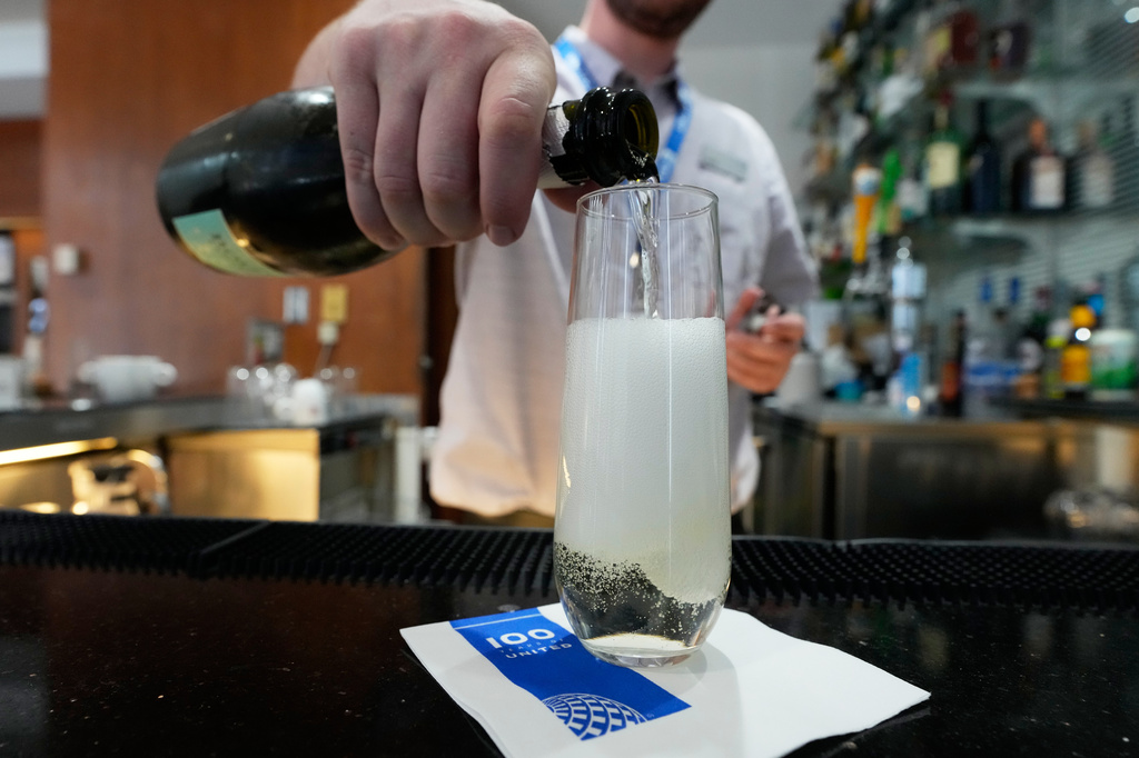A bartender pours a glass of sparkling wine at the United Club lounge, Monday, June 29, 2026, in Minneapolis, Minn. (AP Photo/Chris Carlson)