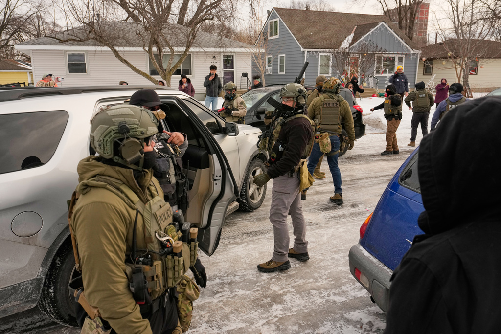 Federal immigration officers make an arrest as bystanders film the incident Sunday, Jan. 11, 2026, in Minneapolis. (AP Photo/John Locher)