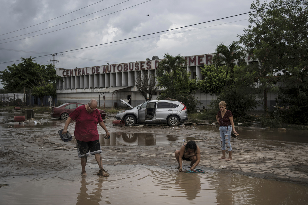 Neighbors walk past the damaged bus station after heavy rainfall in Poza Rica, Veracruz state, Mexico, Saturday, Oct. 11, 2025. (AP Photo/Felix Marquez)
