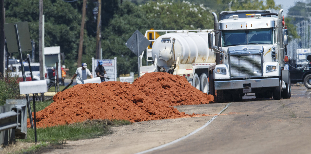 Workers gather along U.S. 51 outside Smitty's Supply in Roseland, La., Monday, Aug. 25, 2025, as cleanup continues after an explosion at the facility that released oil and residue into the air and nearby Tangipahoa River. (David Grunfeld/The Times-Picayune/The New Orleans Advocate via AP)