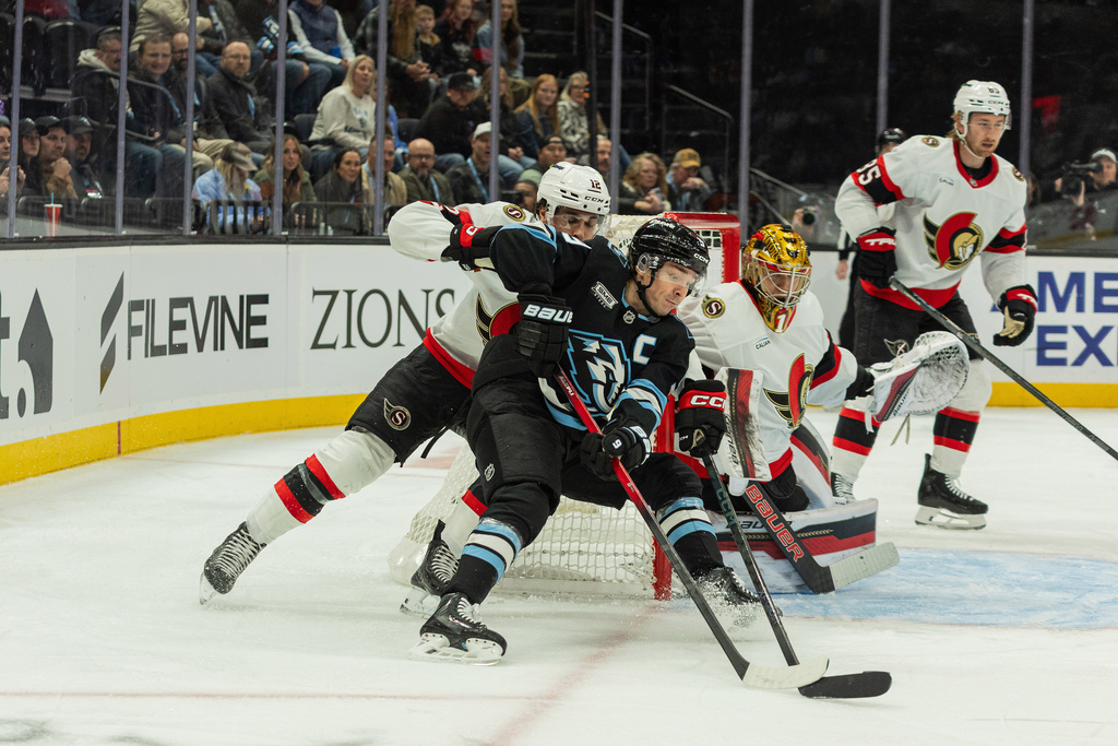 Utah Mammoth center Clayton Keller (9) moves the puck against Ottawa Senators center Shane Pinto (12) and goaltender Mads Sogaard (40) during the first period of an NHL hockey game Wednesday, Jan. 7, 2026, in Salt Lake City. (AP Photo/Melissa Majchrzak)