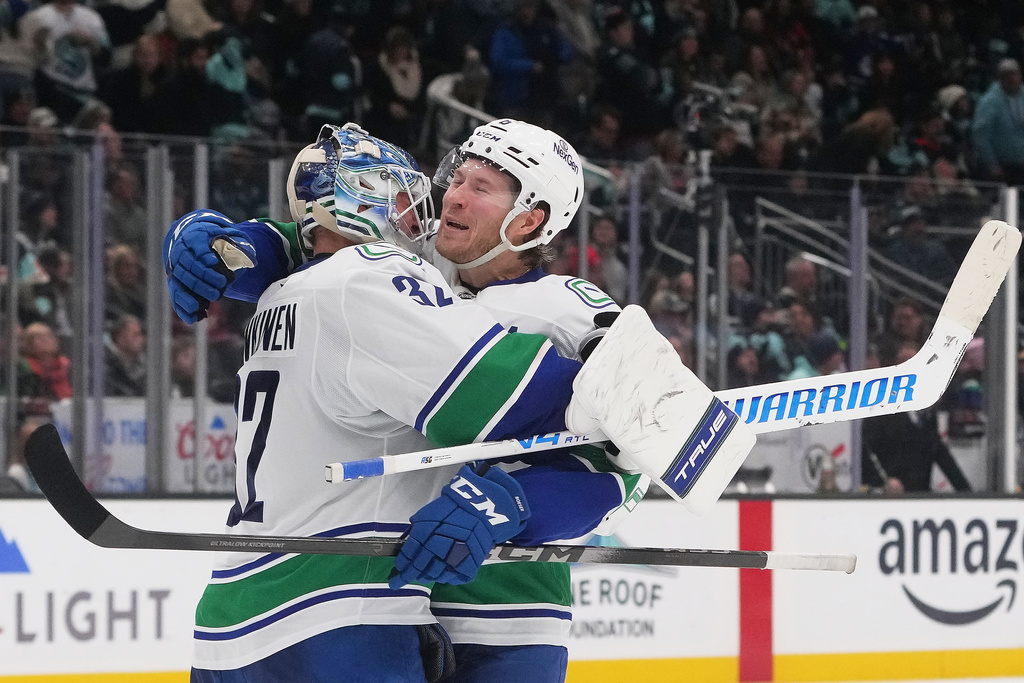 Vancouver Canucks right wing Brock Boeser, facing, celebrates a win in a shootout against the Seattle Kraken with goaltender Kevin Lankinen, left, after an NHL hockey game Monday, Dec. 29, 2025, in Seattle. (AP Photo/Lindsey Wasson)