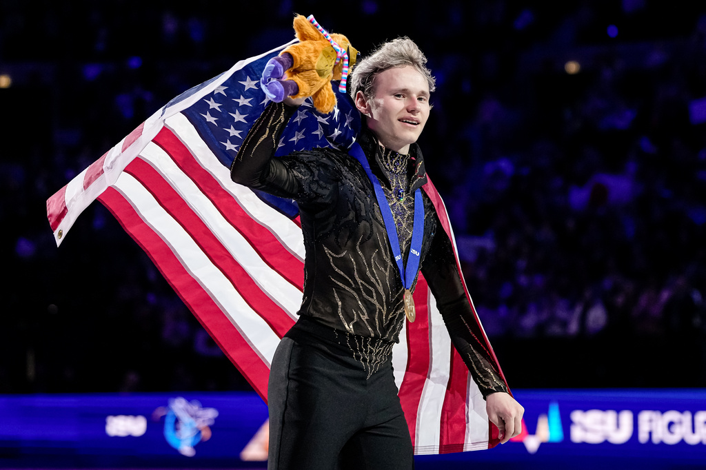 FILE - Gold medalist Ilia Malinin from the United States waves to spectators after the medal ceremony after the men free skating at the Figure Skating World Championships in Prague, Czech Republic, Saturday, March 28, 2026. (AP Photo/Petr David Josek, File)