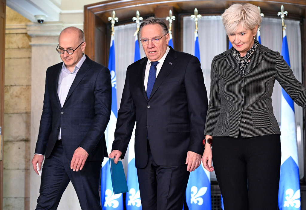 Quebec Premier Francois Legault, accompanied by his chief of staff Martin Koskinen, left, and wife Isabelle Brais, right, walk to a news conference to announce his resignation in Quebec City, on Wednesday, Jan. 14, 2026. (Jacques Boissinot/The Canadian Press via AP)