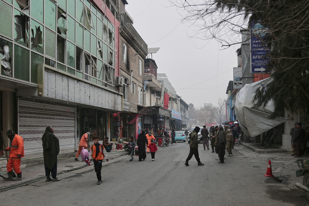 Workers clean the scene as Taliban police secure the area after an explosion at a Chinese restaurant, right, whose entrance is covered with blankets, killed at least seven people, including a Chinese national, a day earlier in Kabul, Afghanistan, Tuesday, Jan. 20, 2026. (AP Photo/Siddiqullah Alizai)