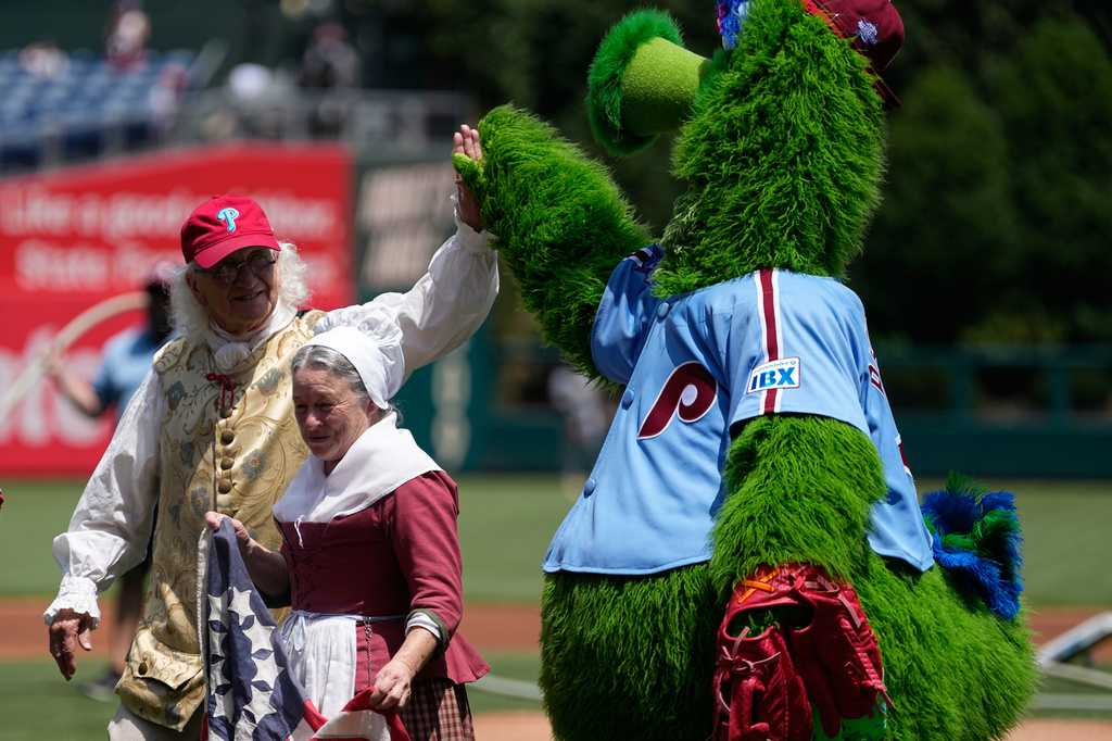 Bill Robling as Benjamin Franklin, left, and Carol Spacht as Betsy Ross, center, greet the Philadelphia Phillies mascot, the Phillie Phanatic before a baseball game between the Phillies and the Pittsburgh Pirates Thursday, July 2, 2026, in Philadelphia. (AP Photo/Matt Slocum)