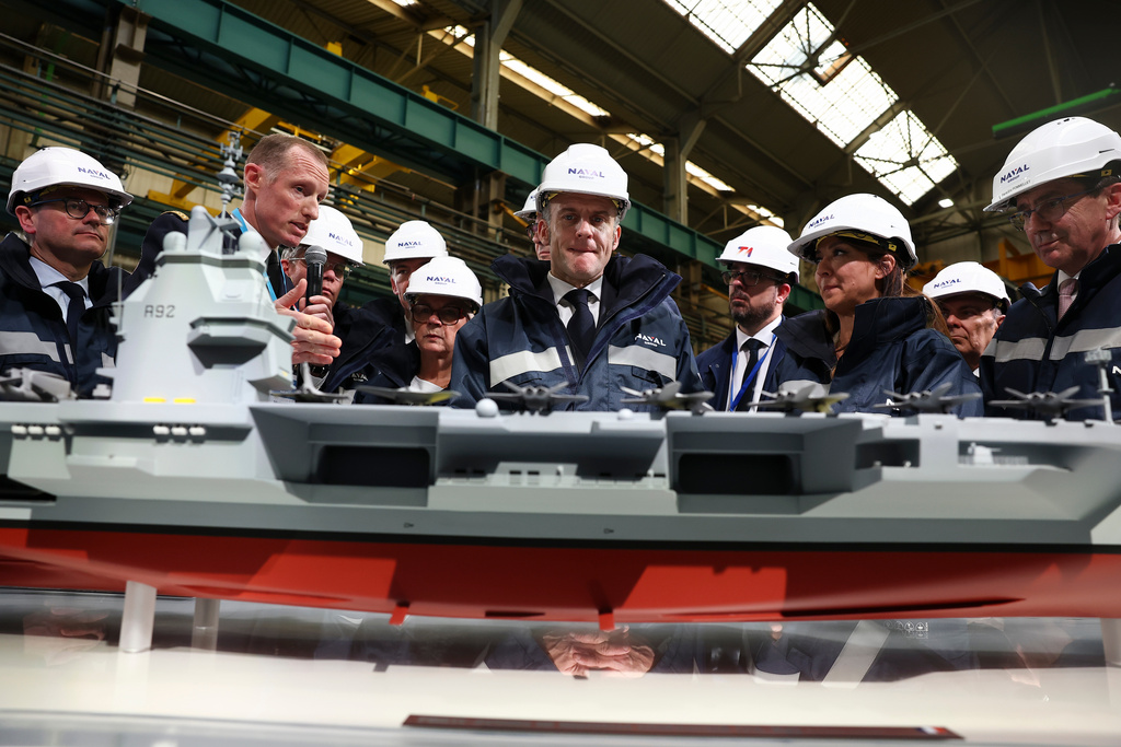 French President Emmanuel Macron, center, stands next to the model of a ship named "France Libre", during his visit to the construction site of Naval Group Nantes-Indret, where the next generation of French aircraft carrier is under construction, in Indret, France, Wednesday, March 18, 2026. (Gonzalo Fuentes/Pool Photo via AP)