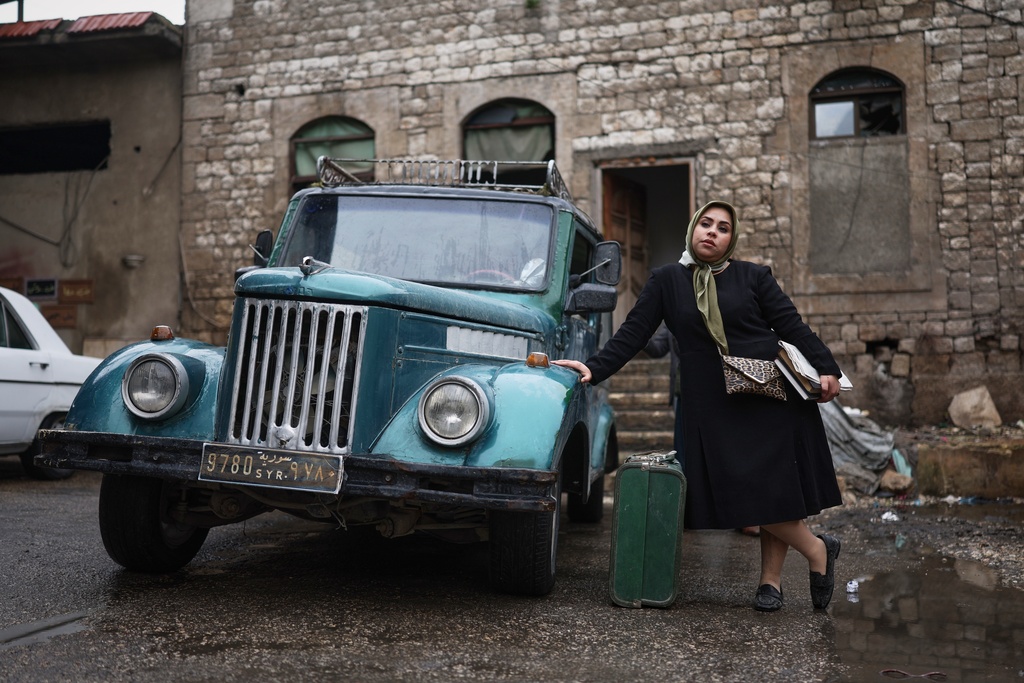 Lamees Al-Ali, an extra in the series, poses for a photograph during the filming of an episode of the TV series "Al-Souriyoun al-Aada" ("The Syrian Enemies"), based on a novel of the same name that was banned under Bashar Assad, along a transformed street in central Aleppo, Syria, Friday, Feb. 13, 2026. (AP Photo/Ghaith Alsayed)