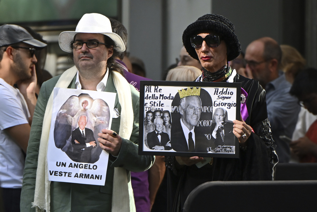 Fans display placards in Italian reading: "An angel wears Armani" outside the Armani/Teatro in Milan, northern Italy, to pay their respects to designer Giorgio Armani, who died Thursday at age 91, Sunday, Sept. 7, 2025. (AP Photo/Nicola Marfisi)