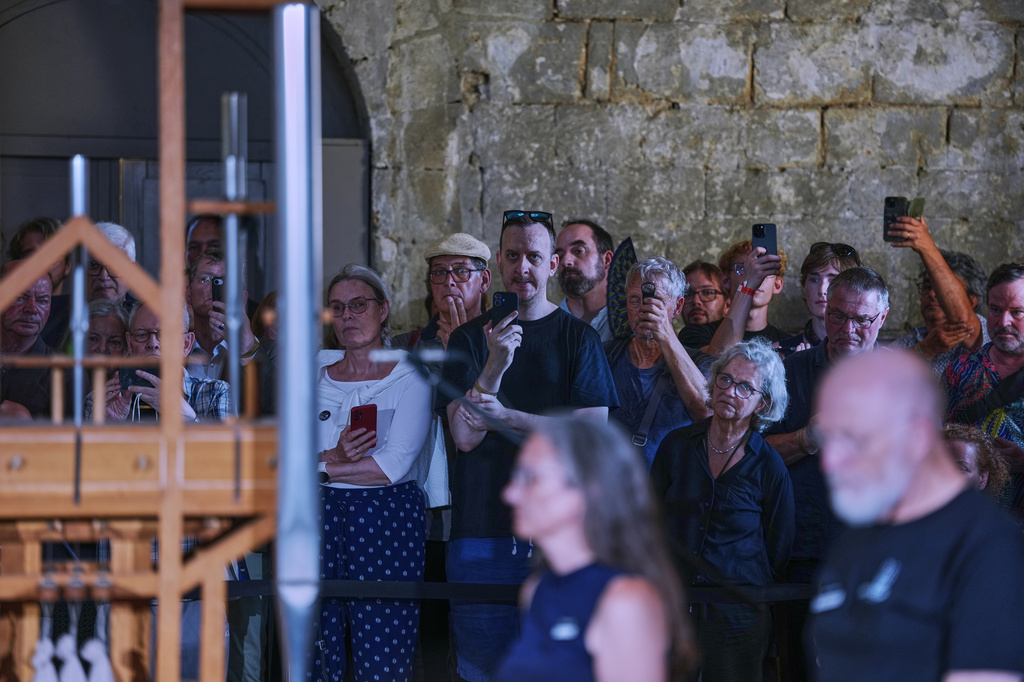 People listen to the sound of the John Cage Organ Project Halberstadt during a chord change on the organ inside the medieval Burchardi Church in Halberstadt, Germany, Wednesday, Aug. 5, 2026. (AP Photo/Markus Schreiber)