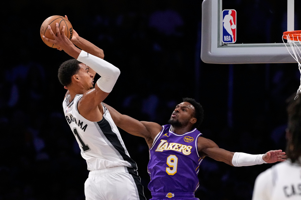 San Antonio Spurs forward Victor Wembanyama, left, goes up fora dunk as Los Angeles Lakers guard Bronny James defends during the first half of an NBA basketball game Wednesday, Nov. 5, 2025, in Los Angeles. (AP Photo/Mark J. Terrill)