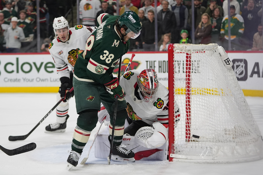 Chicago Blackhawks goaltender Spencer Knight (30) defends the goal as Minnesota Wild right wing Ryan Hartman (38) pressures during the third period of an NHL hockey game, Thursday, March 19, 2026, in St. Paul, Minn. (AP Photo/Abbie Parr)