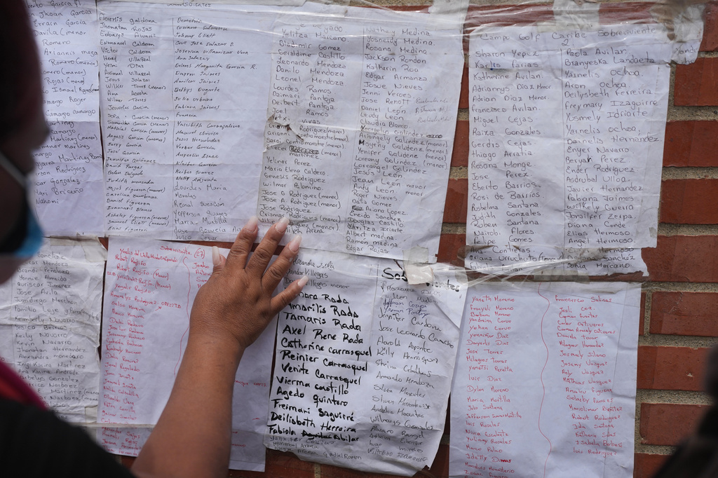 A woman looks for her relatives' names on lists of missing people after deadly earthquakes in La Guaira, Venezuela, Sunday, June 28, 2026. (AP Photo/Matias Delacroix)