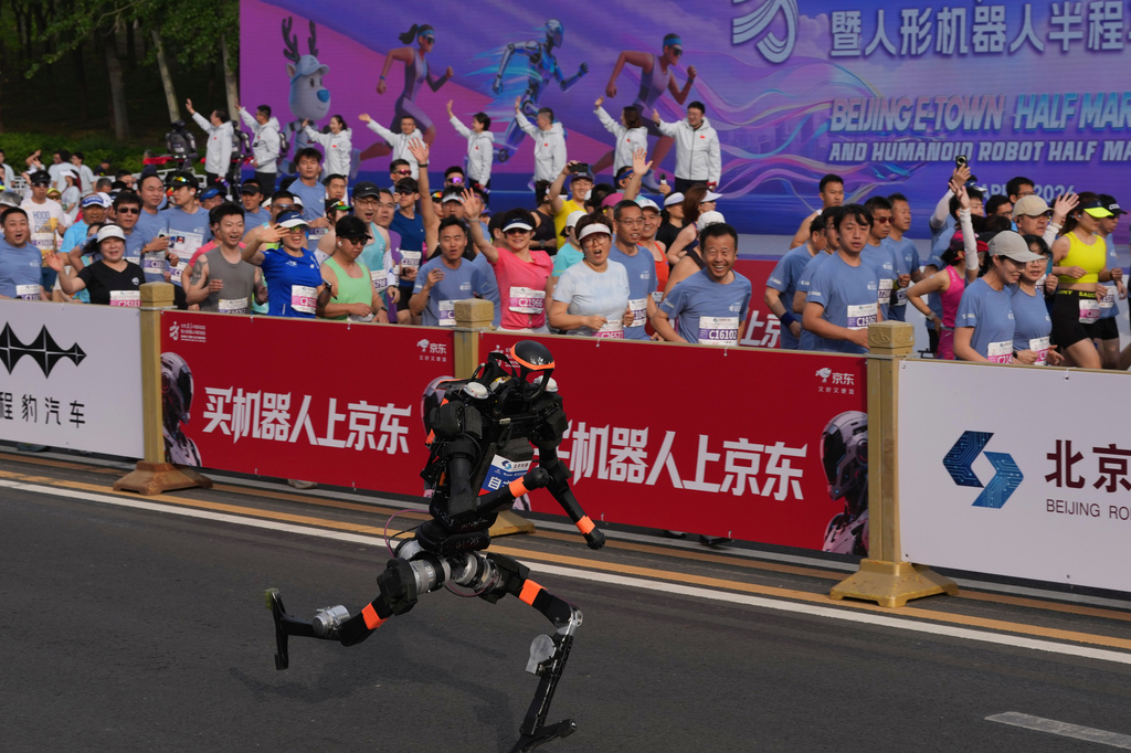 A robot starts off next to human marathon runners for the Beijing E-Town Half Marathon and Humanoid Half Marathon held on the outskirts of Beijing on Sunday April 19, 2026. (AP Photo/Ng Han Guan)