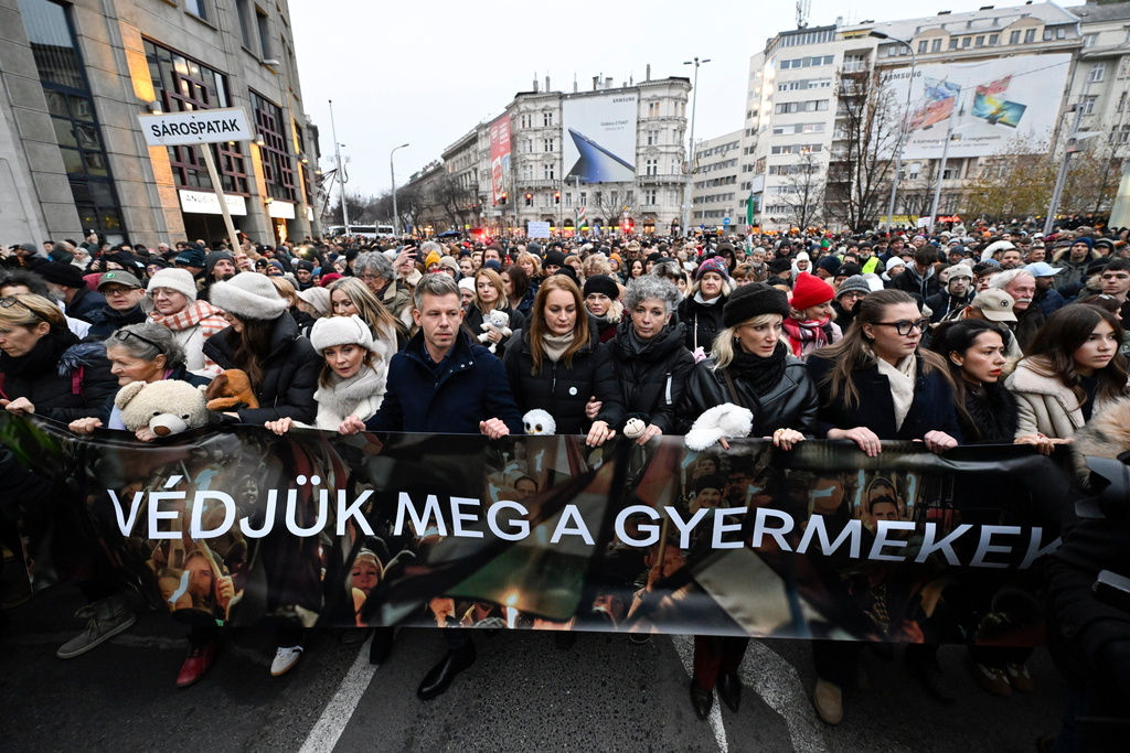 Chairman of the Hungarian opposition Tisza Party Peter Magyar, fifth from left, Vice Chairman of Tisza Party Agnes Forsthoffer, sixth from left, and opera singer Andrea Rost, the party's parliamentary candidate for Jasz-Nagykun-Szolnok County Constituency 1, fourth from right, walk behind a banner reading "Let's protect children" during the Tisza Party demonstration in support of abused children in Budapest, Hungary, Saturday, Dec. 13, 2025. (Robert Hegedus/MTI via AP)