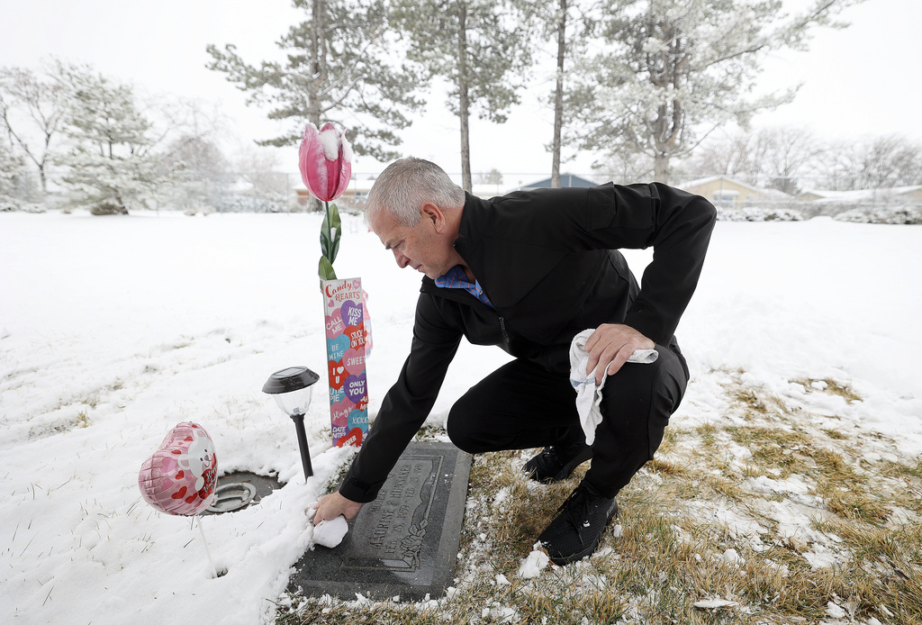 Matt Hunsaker cleans off the grave of his mother Maurine Hunsaker, who was murdered in 1986, at Valley View Memorial Park in West Valley City, Utah, on Friday, Feb. 9, 2024. (Kristin Murphy/The Deseret News via AP)