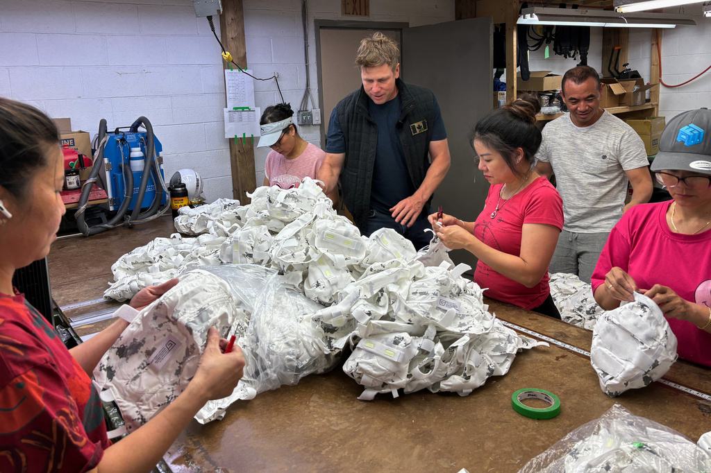 Wuxly CEO James Yurichuk and garment factory owner Aaron Ly inspect military helmet covers on July 20, 2026, in North York, Ontario. (AP Photo/Kelvin Chan) CORRECTION: Family name corrected to Ly, instead of Lyand.