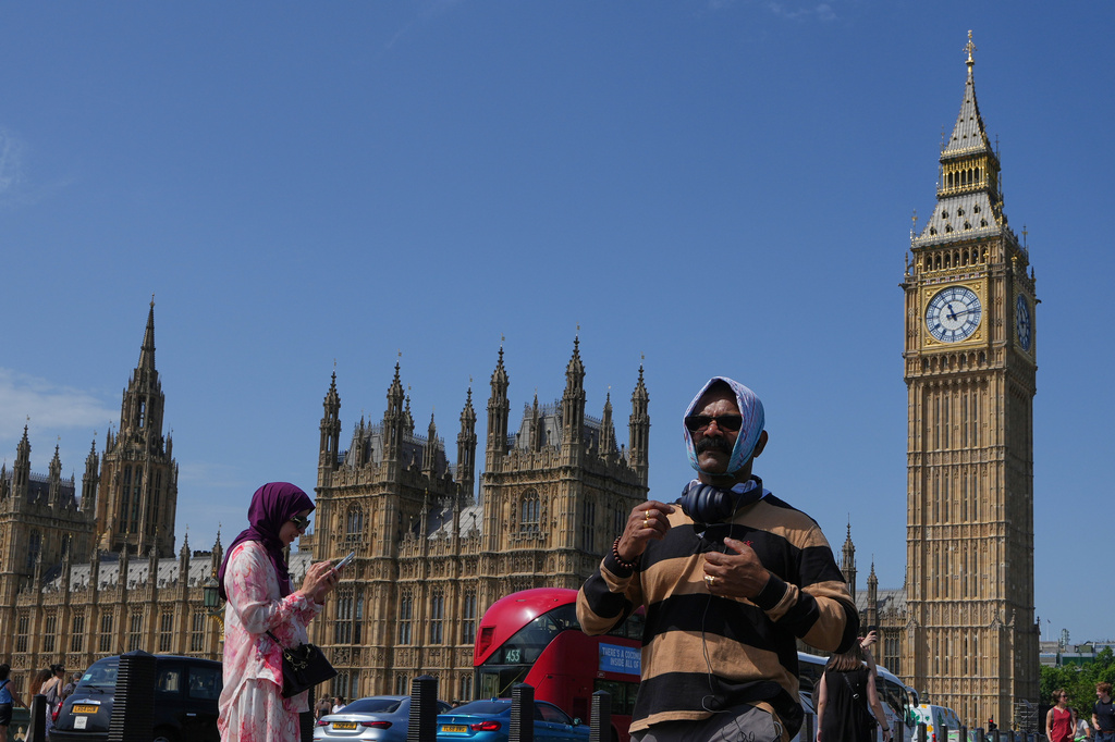 A man shelters from the sun as he crosses Westminster Bridge as a heat wave is predicted in London, Tuesday, June 23, 2026. (AP Photo/Kirsty Wigglesworth)