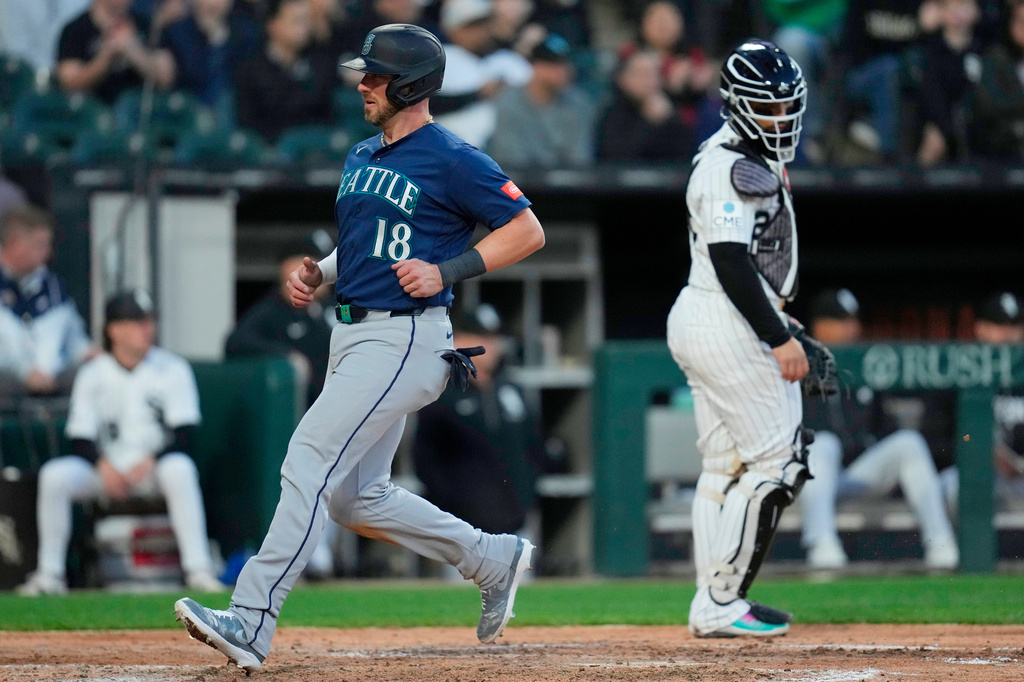 Seattle Mariners' Mitch Garver (18) jogs by Chicago White Sox catcher Edgar Quero, right, to score on a sacrifice fly hit by Rob Refsnyder during the fifth inning of a baseball game Saturday, May 9, 2026, in Chicago. (AP Photo/Erin Hooley)