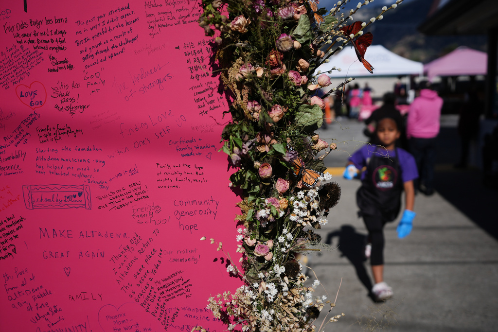 Messages are written on a sign post on a food distribution site for people affected by the wildfires on the one-year anniversary of the Eaton Fire Wednesday, Jan. 7, 2026, in Altadena, Calif. (AP Photo/Gregory Bull)