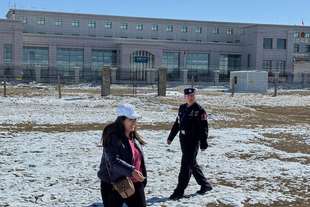 A Chinese police officer patrols near a Nepali tourist posing for a photograph at the Korola border between Nepal and China in Mustang district, Nepal, April 18, 2025. (AP Photo/Niranjan Shrestha)