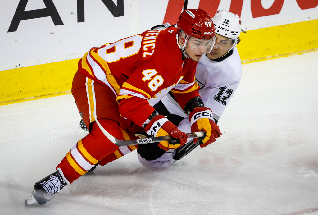 Los Angeles Kings' Trevor Moore, right, is checked by Calgary Flames' Hunter Brzustewicz during the second period of an NHL hockey game in Calgary, Alberta, on Thursday, April 16, 2026. (Jeff McIntosh/The Canadian Press via AP)