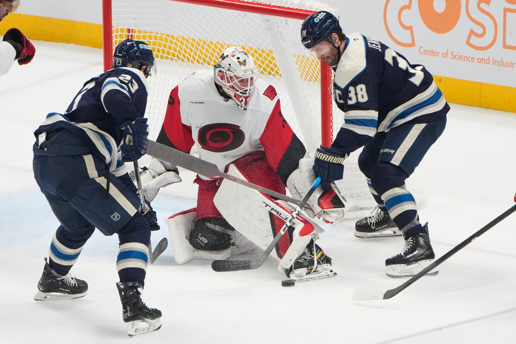 Carolina Hurricanes goaltender Brandon Bussi (32) kicks the puck away from Columbus Blue Jackets center Sean Monahan (23) and center Boone Jenner (38) in the first period of an NHL game in Columbus, Tuesday, March 31, 2026. (AP Photo/Sue Ogrocki)