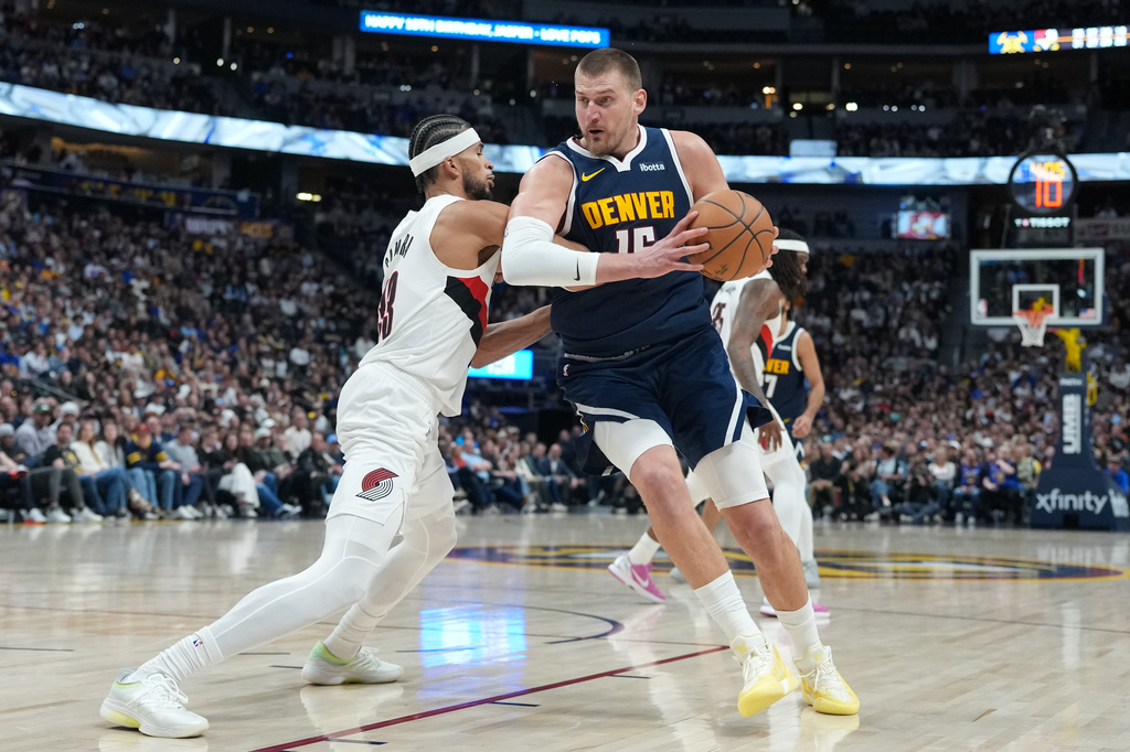 Denver Nuggets center Nikola Jokić, right, drives to the rim as Portland Trail Blazers forward Toumani Camara defends in the second half of an NBA basketball game Monday, April 6, 2026, in Denver. (AP Photo/David Zalubowski)