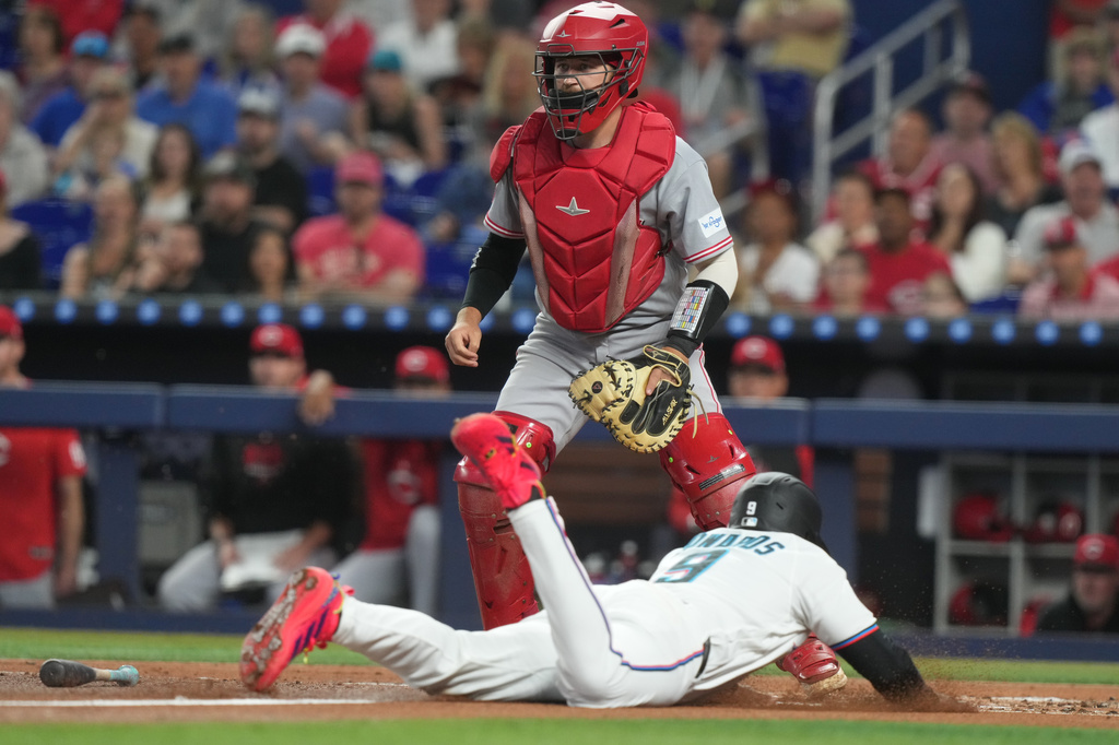 Miami Marlins Xavier Edwards (9) slides into home plate to score as Cincinnati Reds catcher P.J. Higgins wait for the ball the first inning a baseball game Thursday, April 9, 2026, in Miami. (AP Photo/Marta Lavandier)