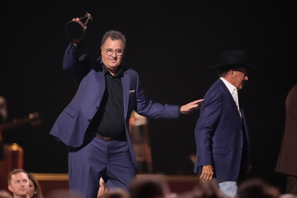 Vince Gill accepts the lifetime achievement award during the 59th Annual Country Music Association Awards on Wednesday, Nov. 19, 2025, at Bridgestone Arena in Nashville, Tenn. George Strait looks on from right.(AP Photo/George Walker IV)