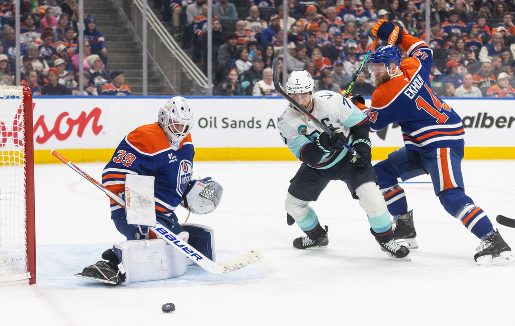Edmonton Oilers goalie Connor Ingram (39) makes the save as Seattle Kraken's Jordan Eberle (7) and Mattias Ekholm (14) battle for the rebound during first period NHL action, in Edmonton on Tuesday, March 31, 2026. (Jason Franson/The Canadian Press via AP)