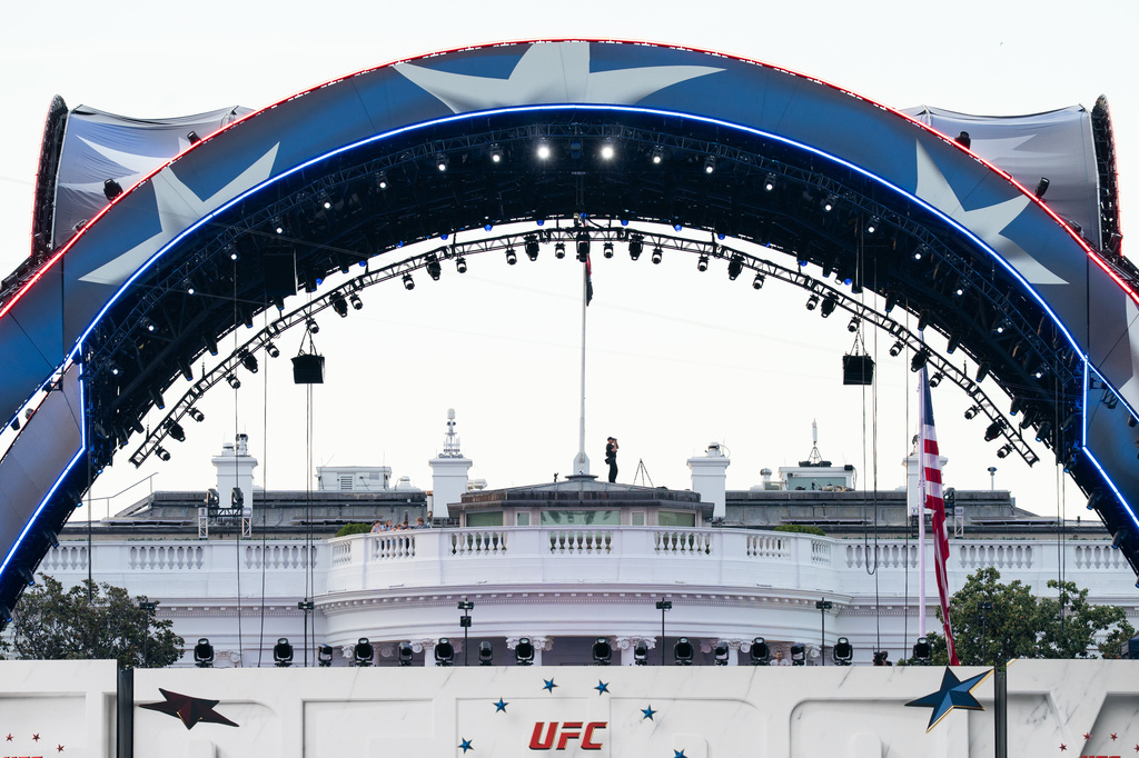Security at the White House looks through a pair of binoculars during the UFC Fan Fest on the White House Ellipse ahead of Sunday's fight on the South Lawn, Saturday, June 13, 2026, in Washington. (AP Photo/Allison Robbert)