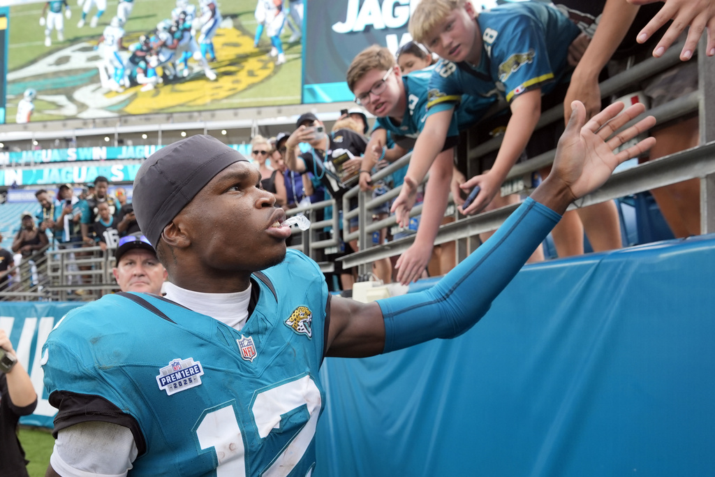 Jacksonville Jaguars wide receiver Travis Hunter (12) signs greets fans after an NFL football game against the Carolina Panthers, Sunday, Sept. 7, 2025, in Jacksonville, Fla. (AP Photo/John Raoux)