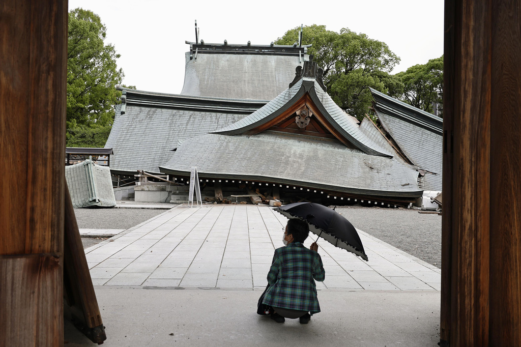 A visitor looks at the fallen roofs of the Yatsuhiro Shrine, a day after an earthquake in Yatsushiro, Kumamoto prefecture, Wednesday, July 29, 2026.(Juntaro Yokoyama/Kyodo News via AP)