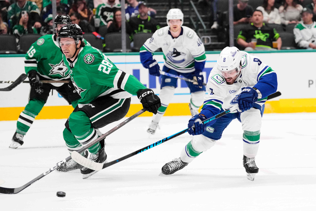 Vancouver Canucks right wing Conor Garland (8) shoots and scores on a shot behind Dallas Stars defenseman Alexander Petrovic (28) in the second period of an NHL hockey game Thursday, Oct. 16, 2025, in Dallas. (AP Photo/Tony Gutierrez)