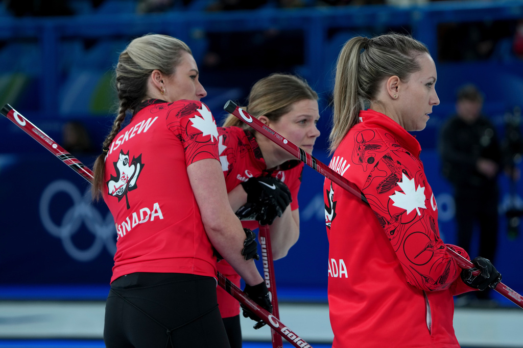 Canada's Emma Miskew, left, Rachel Homan, right, and Sarah Wilkes study the situation during a women's curling semifinal match against Sweden, at the 2026 Winter Olympics, in Cortina d'Ampezzo, Italy, Friday, Feb. 20, 2026. (AP Photo/Misper Apawu)