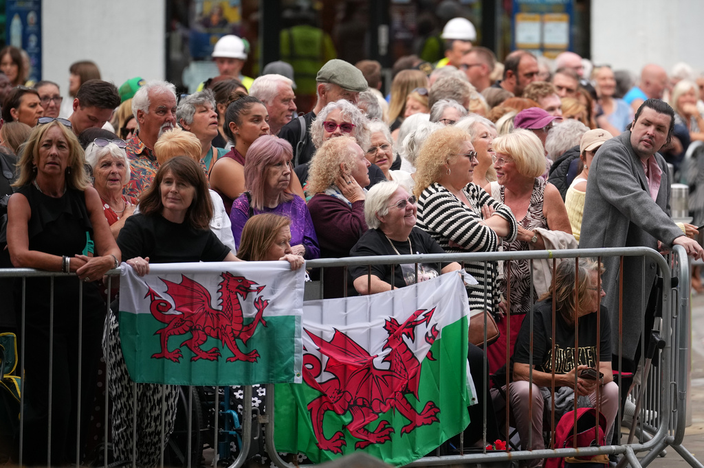 People wait behind barriers for the start of the funeral of Bonnie Tyler at St. Mary's Church in Swansea, Wales, Monday, Aug. 17, 2026. (AP Photo/Alastair Grant)