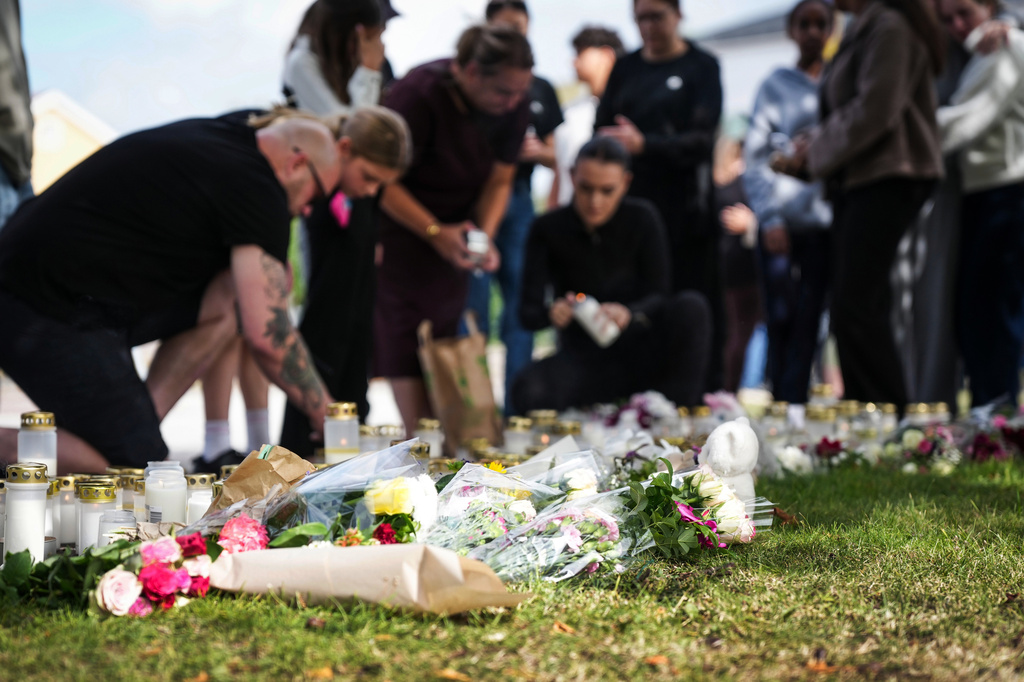 People leave flowers and candles at a makeshift memorial outside a school in Fagersta, Sweden, Saturday Aug. 22, 2026, the day after an 18-year-old with a sword attacked the school killing one person and seriously injuring two others. (Magnus Lejhall/TT via AP)