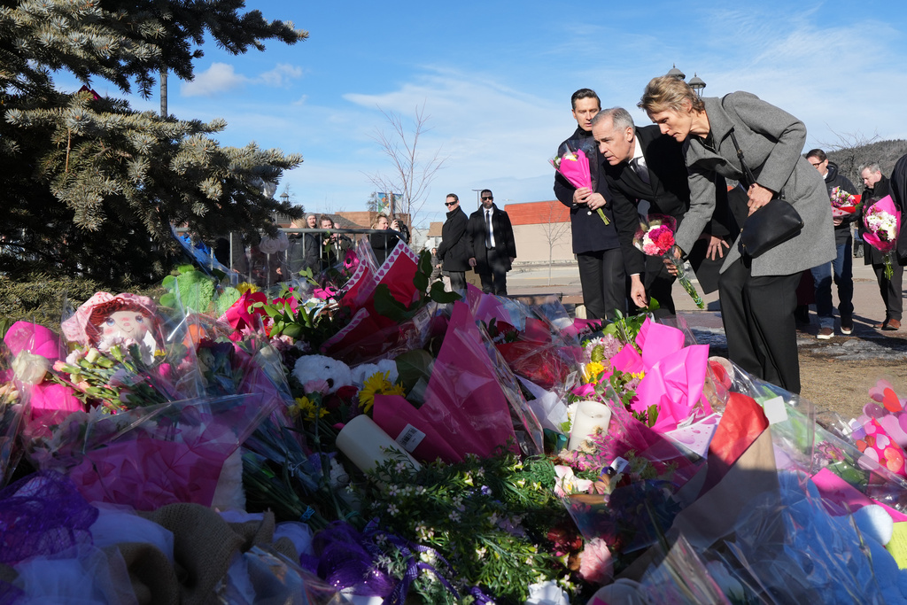 Canada's Prime Minister Mark Carney and his wife Diana Fox Carney place flowers at a memorial for the victims of a mass shooting, in Tumbler Ridge, B.C., Friday, Feb. 13, 2026. (Christinne Muschi/The Canadian Press via AP)