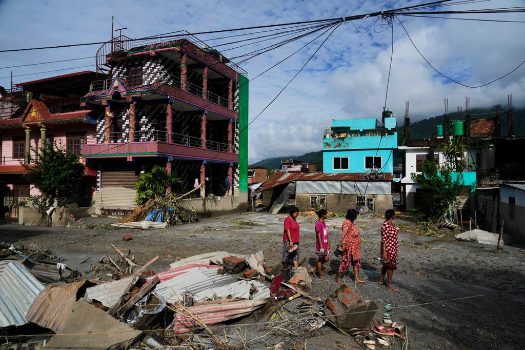 People walk past damage in the aftermath of flash floods in Devighat in the Nuwakot district in Nepal, Thursday, Aug 27, 2026. (AP Photo/Niranjan Shrestha)