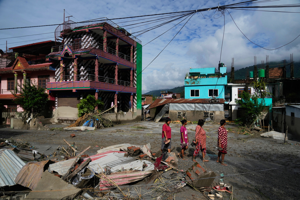 People walk past damage in the aftermath of flash floods in Devighat in the Nuwakot district in Nepal, Thursday, Aug. 27, 2026. (AP Photo/Niranjan Shrestha)